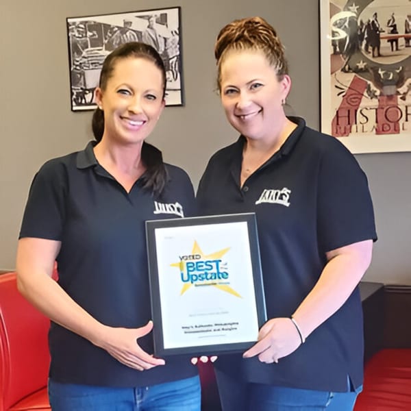 Two smiling women in black Inky's shirts proudly hold a "Voted Best Upstate" award plaque.