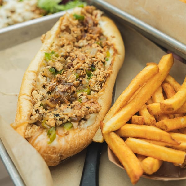 Inky's chicken cheesesteak with onions and peppers, served with a side of golden french fries.
